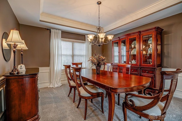 dining room with dark carpet, a wainscoted wall, a raised ceiling, and a chandelier