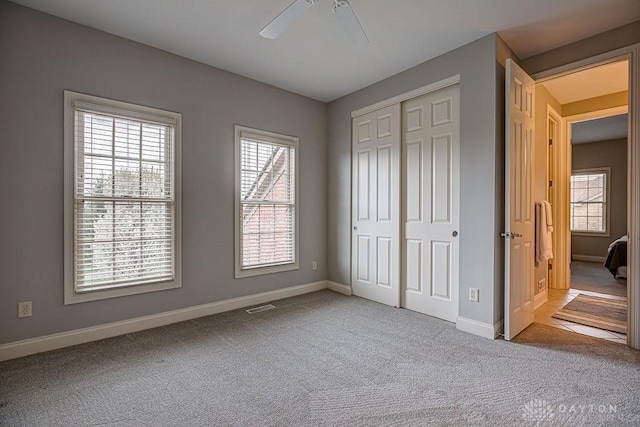 unfurnished bedroom featuring carpet floors, baseboards, a closet, and visible vents