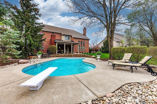 view of swimming pool with a patio area, a fenced in pool, and a diving board