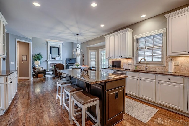 kitchen featuring a sink, a breakfast bar, dark stone countertops, and white cabinetry