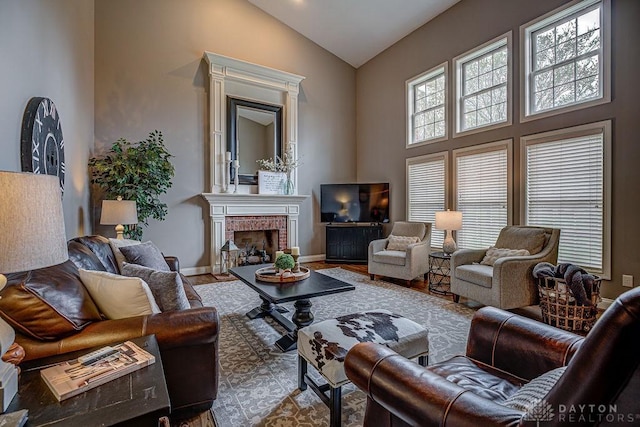 living room with high vaulted ceiling, a fireplace, baseboards, and wood finished floors