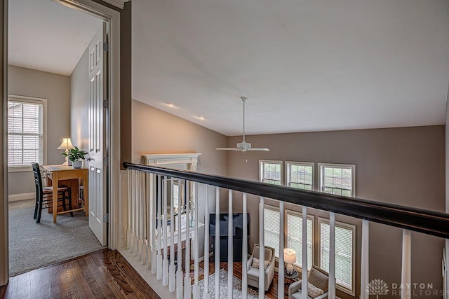 hallway featuring wood finished floors, baseboards, and lofted ceiling
