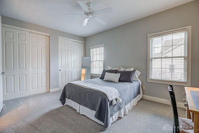 carpeted bedroom featuring baseboards, a ceiling fan, and multiple closets
