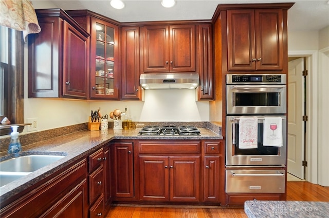 1458 Westwicke Pl, Washington Twp, OH 45459 - kitchen with ventilation hood, dark brown cabinets, a warming drawer, light wood finished floors, and stainless steel appliances