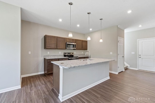 1226 Heathgate Way, Fairborn, OH 45324 - kitchen with appliances with stainless steel finishes, dark wood-style floors, a kitchen island with sink, hanging light fixtures, and light stone counters