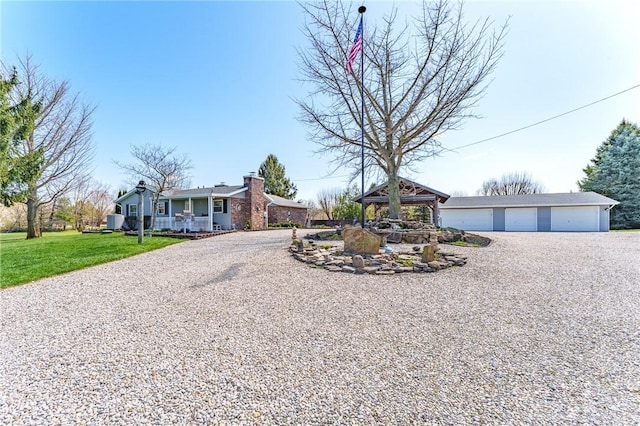 view of front of house with a detached garage, an outdoor structure, gravel driveway, a front lawn, and a gazebo
