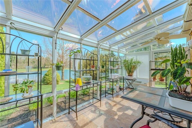 sunroom featuring a water view, a ceiling fan, and a healthy amount of sunlight