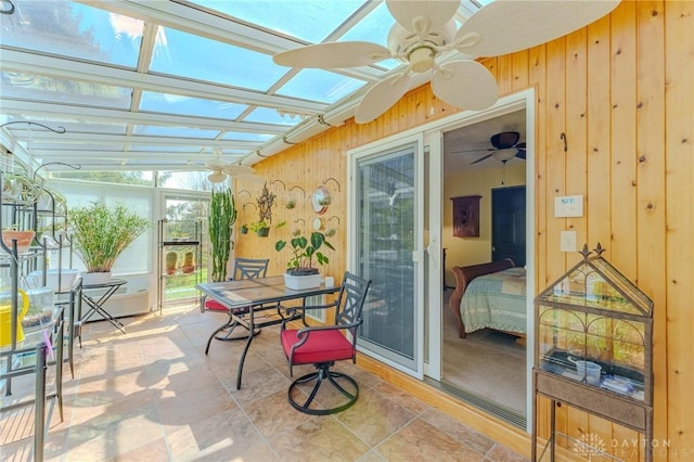 sunroom featuring wooden walls, a skylight, a ceiling fan, and outdoor dining area