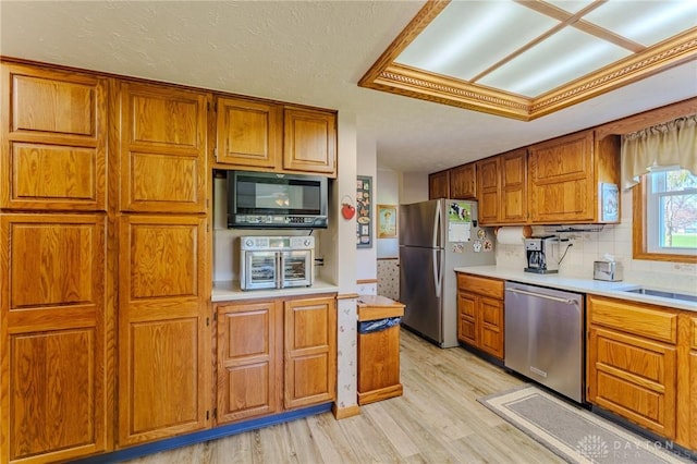 kitchen featuring light countertops, brown cabinetry, light wood-type flooring, and stainless steel appliances
