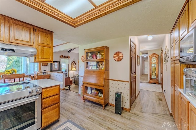 kitchen featuring light wood-type flooring, stainless steel range with electric stovetop, under cabinet range hood, light countertops, and brown cabinets