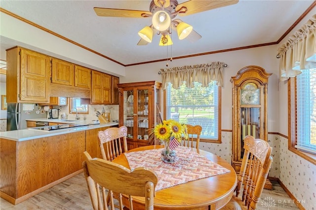 dining room featuring ornamental molding, light wood-style flooring, a ceiling fan, and a healthy amount of sunlight