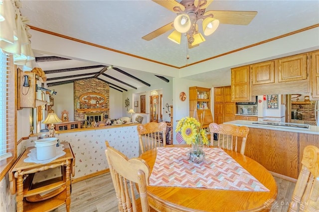 dining space featuring a fireplace, light wood finished floors, lofted ceiling with beams, and ceiling fan