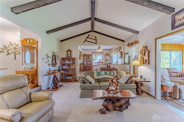 carpeted living room with ceiling fan and vaulted ceiling with beams