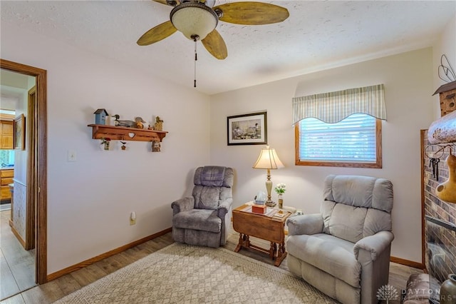 sitting room with a textured ceiling, wood finished floors, ceiling fan, and baseboards