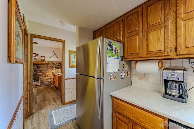 kitchen featuring brown cabinetry, light wood-style floors, light countertops, and freestanding refrigerator