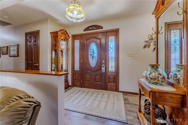 entryway featuring a textured ceiling, baseboards, wood finished floors, and a healthy amount of sunlight