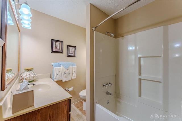 full bath with vanity, baseboards, a textured ceiling, toilet, and bathtub / shower combination