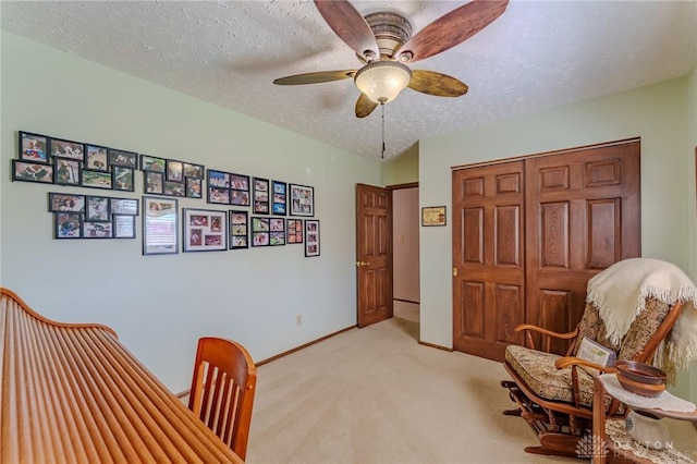 office area featuring baseboards, light colored carpet, a textured ceiling, and ceiling fan