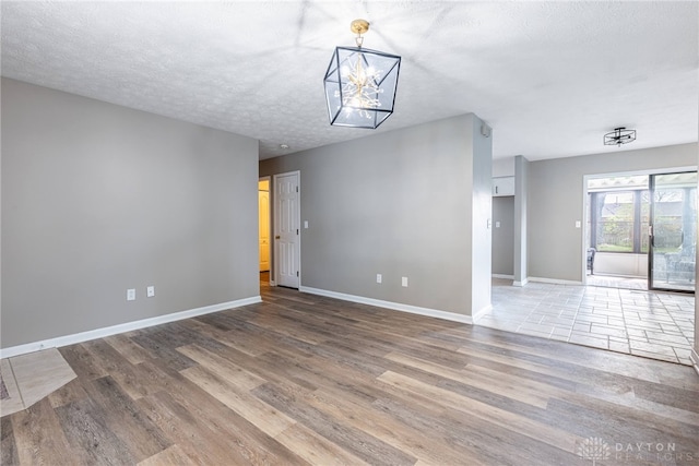 1917 Beckert Dr, Piqua, OH 45356 - spare room featuring wood finished floors, baseboards, a chandelier, and a textured ceiling