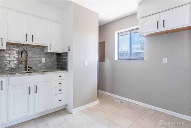 1917 Beckert Dr, Piqua, OH 45356 - kitchen featuring a sink, tasteful backsplash, baseboards, white cabinets, and light stone counters