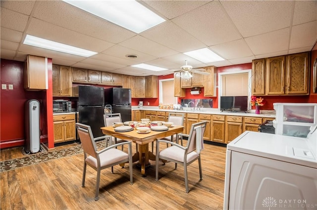 7045 US-40, New Carlisle, OH 45344 - kitchen featuring light wood-style floors, light countertops, freestanding refrigerator, a paneled ceiling, and brown cabinets