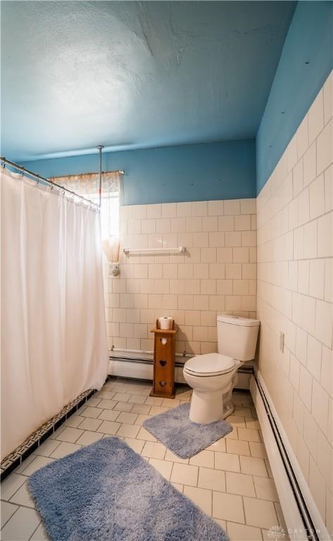 7045 US-40, New Carlisle, OH 45344 - bathroom featuring tile walls, a baseboard radiator, toilet, and tile patterned flooring