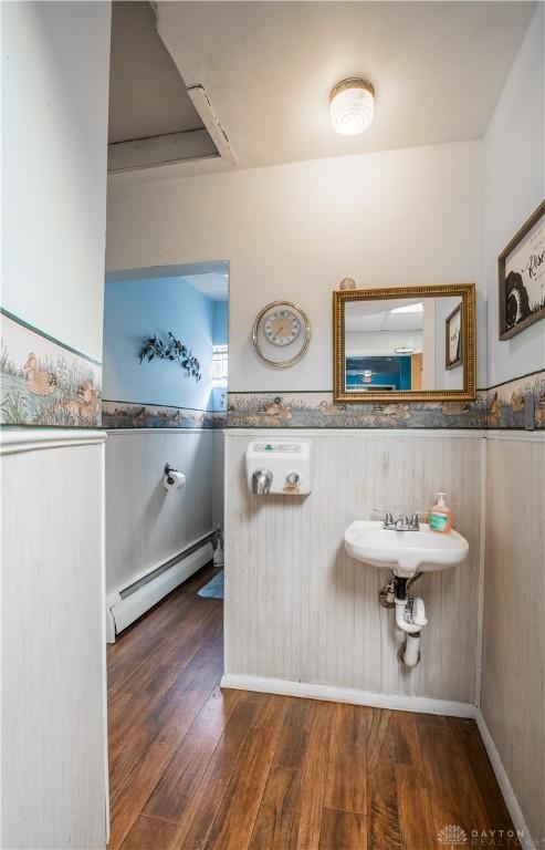 7045 US-40, New Carlisle, OH 45344 - bathroom featuring a baseboard radiator, wood-type flooring, and wainscoting