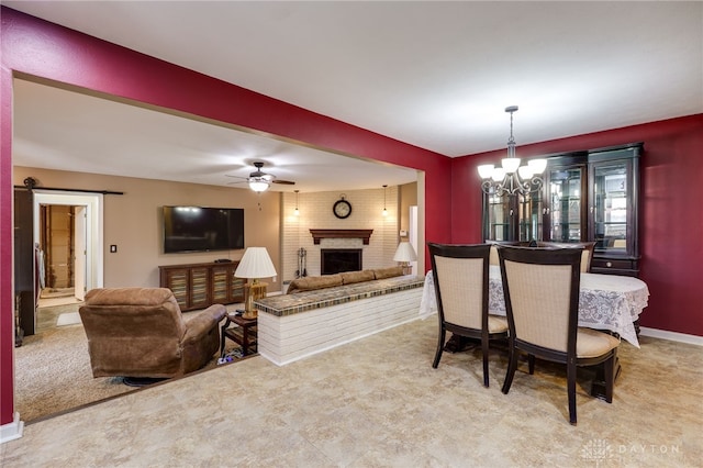 carpeted dining room featuring a brick fireplace and ceiling fan with notable chandelier
