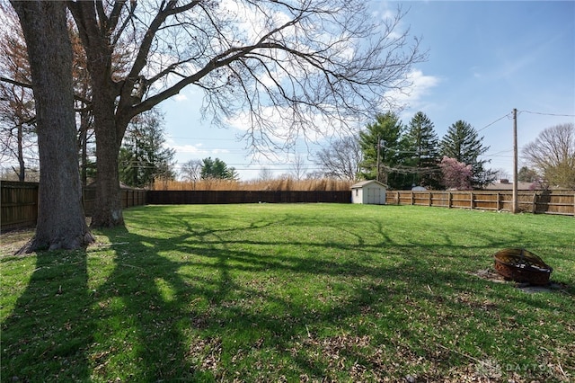 view of yard featuring a storage shed, a fenced backyard, an outdoor fire pit, and an outdoor structure