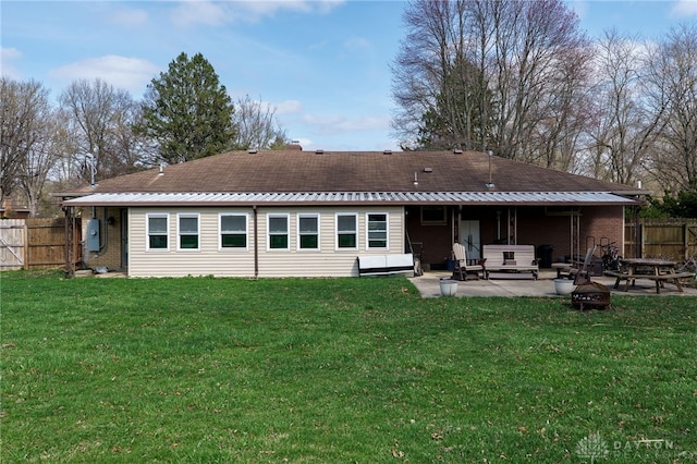 back of house featuring a hot tub, a patio area, an outdoor fire pit, a yard, and fence