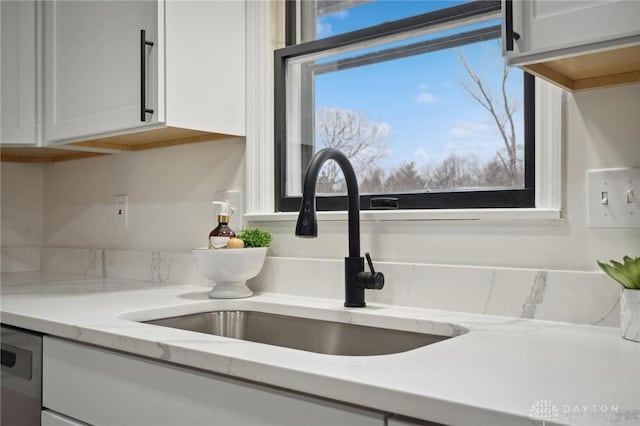 5850 Weidner Rd, Springboro, OH 45066 - interior details featuring light stone counters, stainless steel dishwasher, a sink, and white cabinets