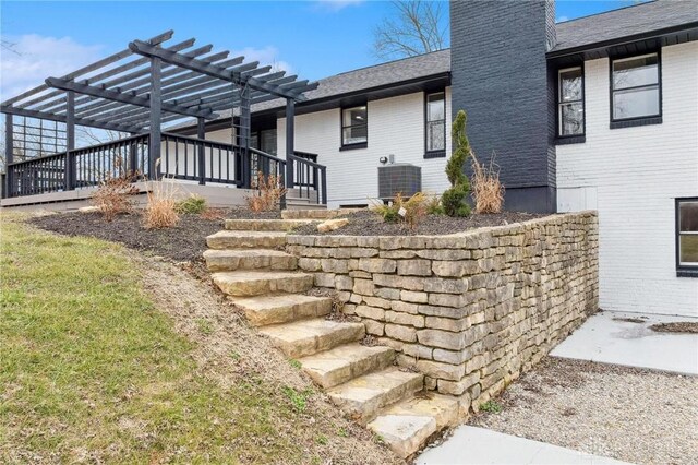 5850 Weidner Rd, Springboro, OH 45066 - exterior space with roof with shingles, a chimney, a pergola, cooling unit, and brick siding