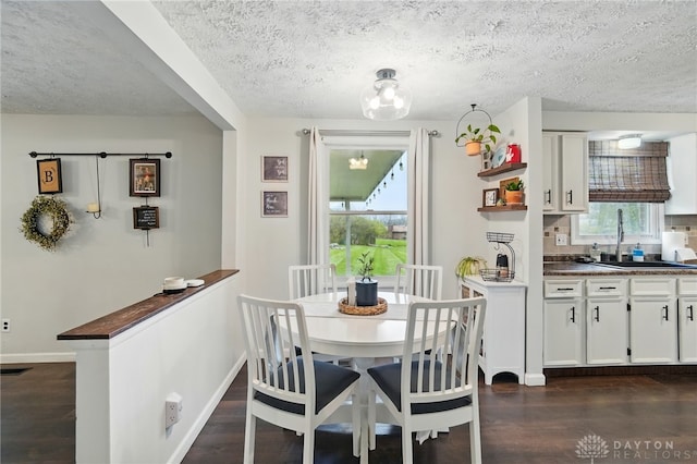 dining space with dark wood-type flooring, baseboards, and a textured ceiling