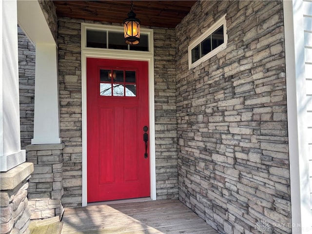 view of exterior entry featuring stone siding and covered porch