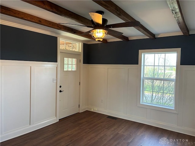 spare room with a decorative wall, dark wood-type flooring, visible vents, and beam ceiling