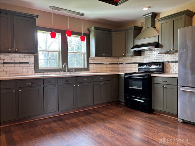 kitchen with dark wood-style flooring, light countertops, premium range hood, freestanding refrigerator, and black electric range oven