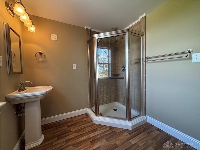 full bathroom featuring baseboards, a sink, a stall shower, and wood finished floors