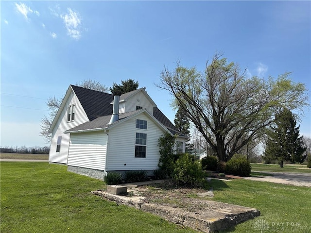 view of home's exterior with a yard and a shingled roof
