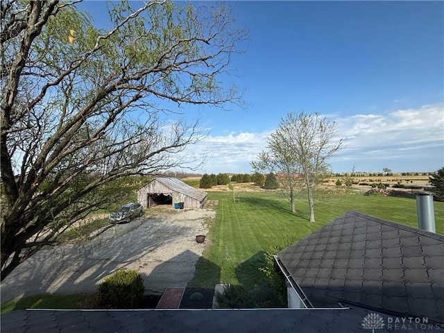 view of yard featuring a rural view, an outdoor structure, and an outbuilding