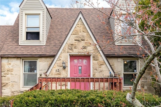 view of front of home featuring stone siding and roof with shingles