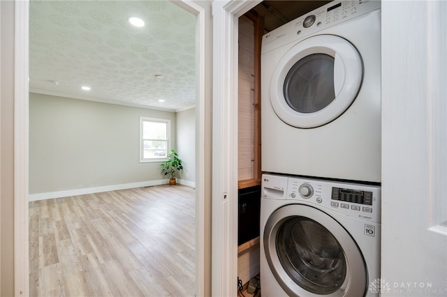 laundry area featuring stacked washer and dryer, baseboards, recessed lighting, wood finished floors, and laundry area