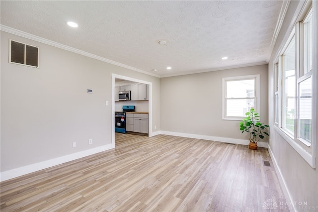 spare room with a textured ceiling, light wood-style flooring, visible vents, and crown molding