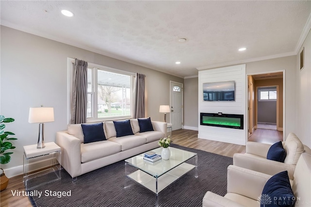 living area featuring baseboards, recessed lighting, wood finished floors, a fireplace, and ornamental molding