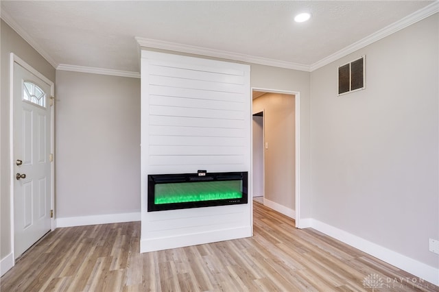 entrance foyer with wood finished floors, visible vents, ornamental molding, baseboards, and a fireplace