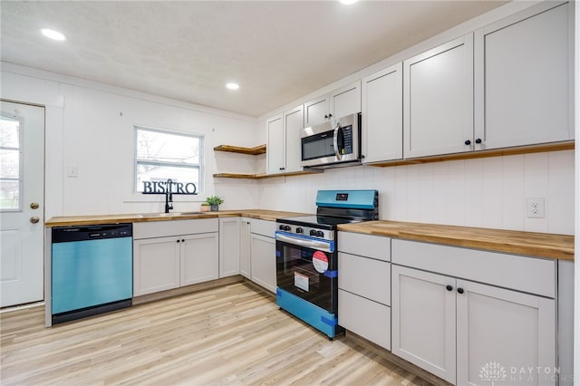 kitchen with wood counters, open shelves, stainless steel appliances, and a sink
