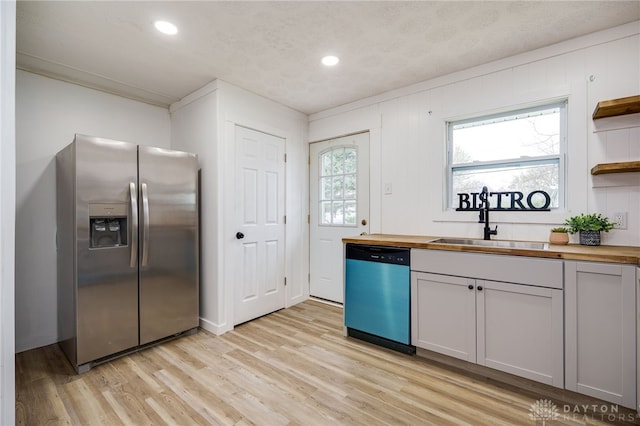kitchen with dishwashing machine, stainless steel fridge, wooden counters, and a sink