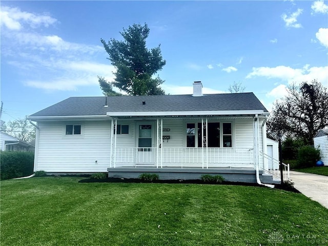 view of front of home featuring a chimney, a front yard, and covered porch
