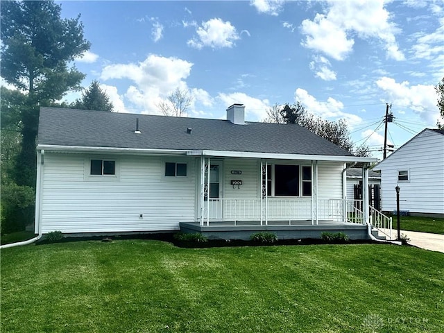 view of front of property with a chimney, a front lawn, a shingled roof, and covered porch