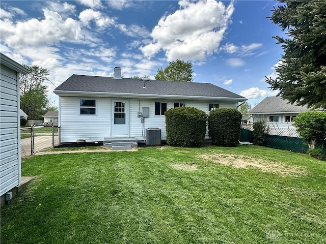 back of property featuring fence, entry steps, and a yard