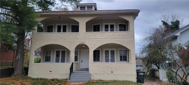 view of front of property featuring fence, a balcony, and stucco siding